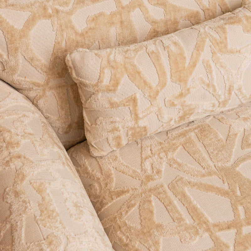 Close-up of upholstered furniture in a warm beige and cream tone with a raised geometric jacquard pattern.