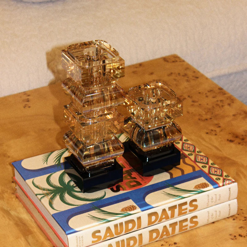 Decorative glass pieces on top of a book titled 'Saudi Dates' on a wooden surface.