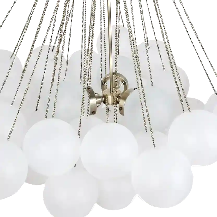 A close-up of a modern chandelier with multiple frosted white spherical glass shades suspended by thin silver chains from a central brushed brass fixture.